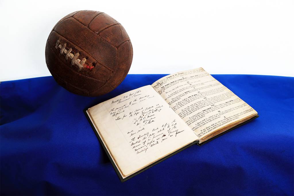 O livro com as primeiras regras do futebol e a bola utilizada para jogos de futebol da época