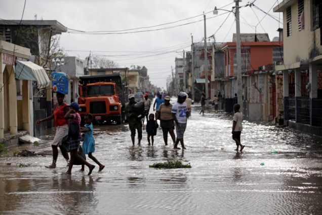 Civis tentam recuperar alguns objetos após a passagem do furacão Matthew, no Haiti