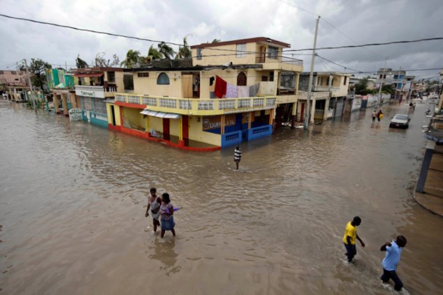 Civis tentam recuperar alguns objetos após a passagem do furacão Matthew, no Haiti