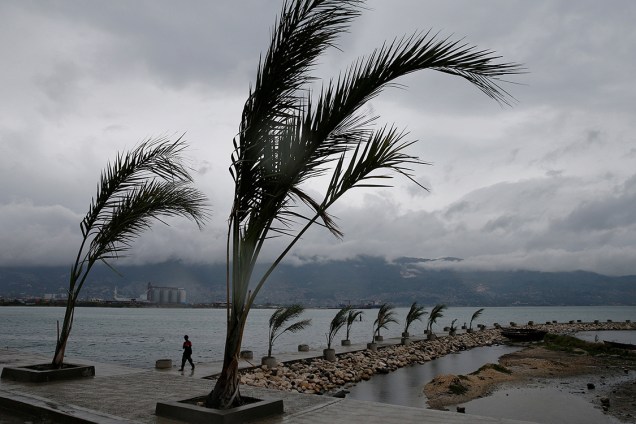 Homem caminha no píer de Porto Príncipe, enquanto o furacão Matthew se aproxima da região