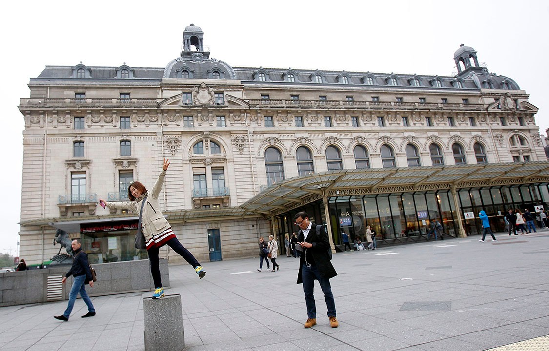 Turista se diverte em frente ao Museu d'Orsay, em Paris
