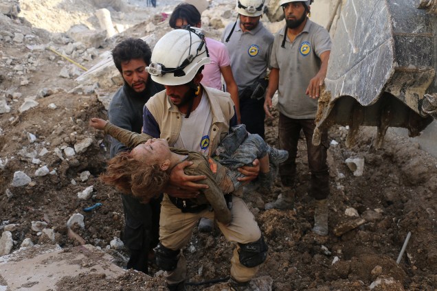 Voluntário de defesa civil síria, segura o corpo de uma criança retirado dos escombros na sequência de um ataque aéreo das forças governamentais no bairro controlado pelos rebeldes de Karm Homad, norte de Aleppo - 04/10/2016