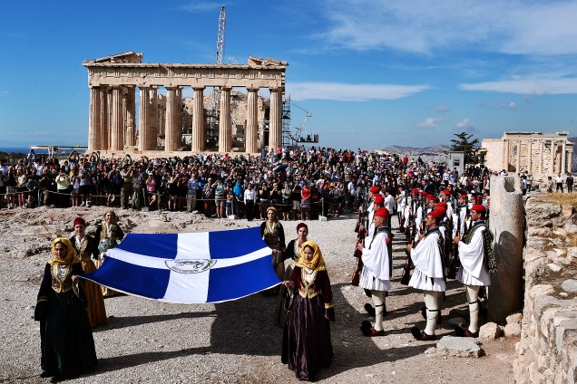 Mulheres em vestidos tradicionais carregam uma bandeira grega durante cerimônia que marca a desocupação alemã na Acrópole em Atenas, na Grécia - 12-10-2016
