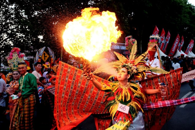 Jovem vestida com roupas tradicionais cospe fogo durante o Carnaval de Makassar, na província de Sulawesi do Sul, na Indonésia