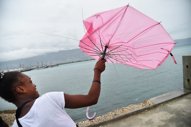 Garota tenta consertar seu guarda-chuva, que foi quebrado pelo vento durante a possível chegada do furacão Matthew, na capital do Haiti Port-au-Prince - 03-10-2016