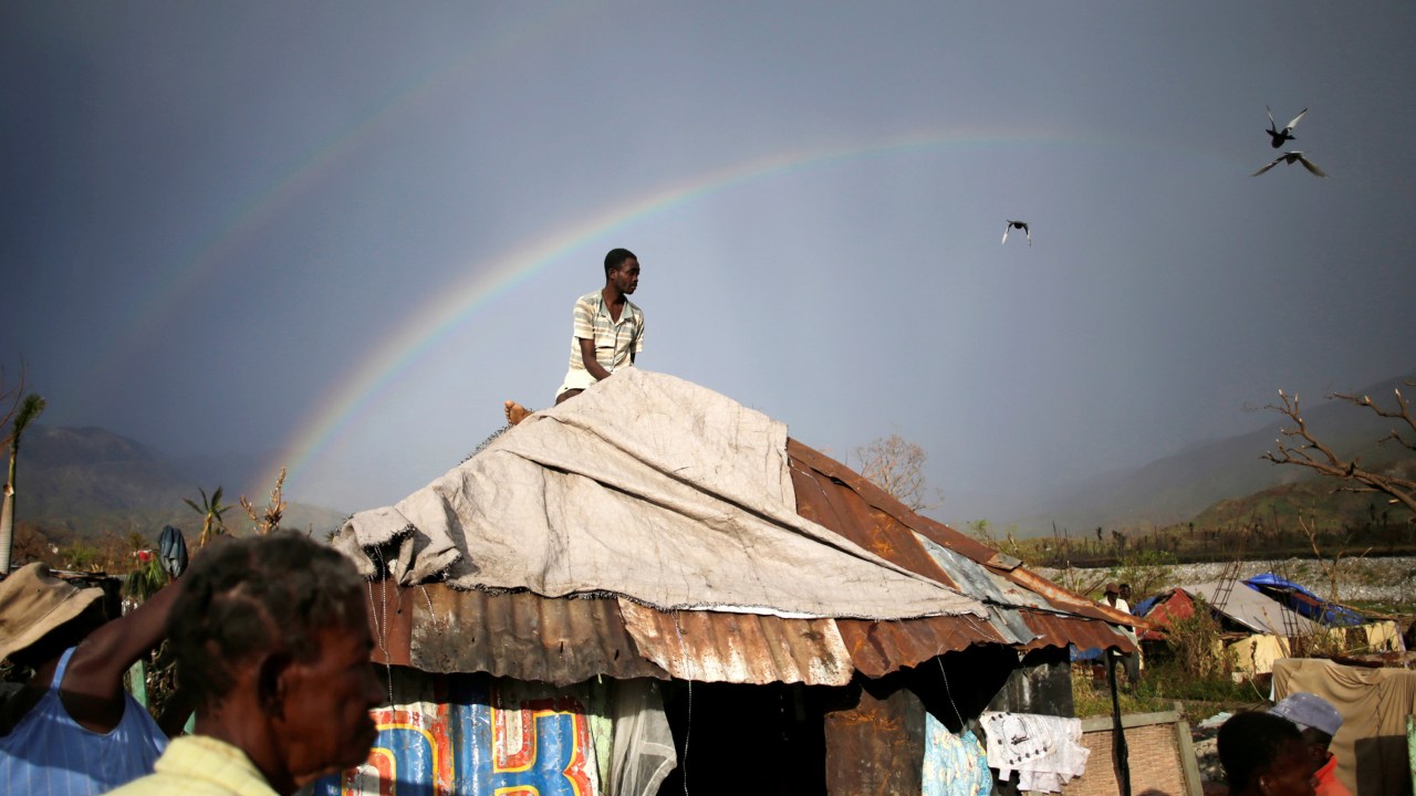 Homem tenta cobrir o telhado de sua casa, após passagem do furacão Matthew em Les Anglais, Haiti