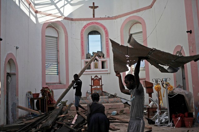 Fiéis retiram escombros de dentro de uma igreja, na pequena cidade de Les Anglais, após passagem do furacão Matthew, que deixou mais de mil mortos no Haiti - 13/10/2016