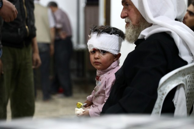 Criança ferida espera após receber tratamento em um hospital improvisado na sequência de ataques aéreos na cidade controlada pelos rebeldes de Douma, periferia de Damasco, na Síria - 03/10/2016