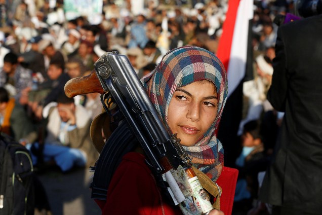 Menina é fotografada um rifle durante uma manifestação dos seguidores do movimento xiita Houthi comemorando a morte de Imam Zaid bin Ali em Saná, no Iêmen - 26-10-2016