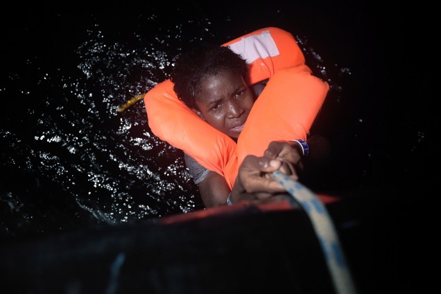 Mulher se agarra a uma corda durante uma operação de resgate de imigrantes na costa da Líbia, no Mar Mediterrâneo