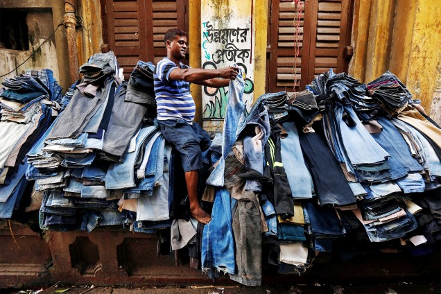 Vendedor comercializa calças de segunda mão em Calcutá, na Índia - 26/10/2016