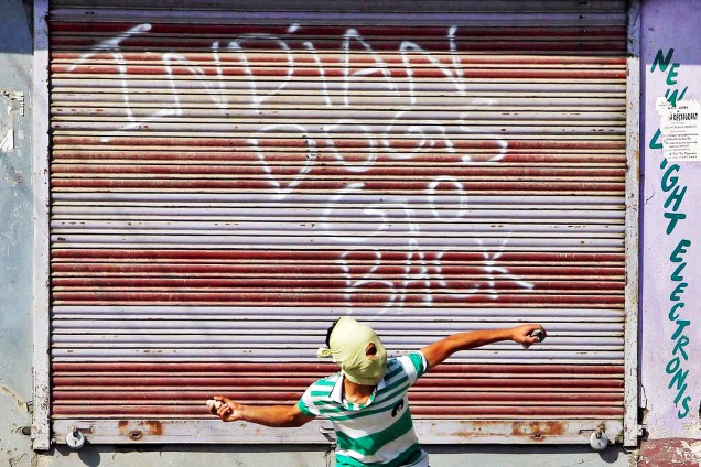 Manifestante lança pedra contra policiais indianos em protesto realizado em Srinagar, na região da Caxemira - 07/10/2016