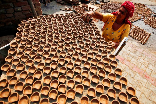 Mulher prepara lâmpadas de barro que serão utilizadas como decoração em residências, no festival religioso de Diwali, na Índia - 07/10/2016