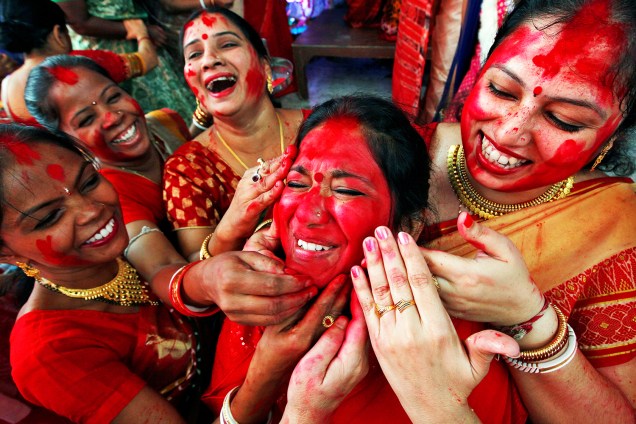 Mulheres pintam rostos com pó vermelho no festival Durga Puja, realizado em Chandigarh, na Índia - 11/10/2016