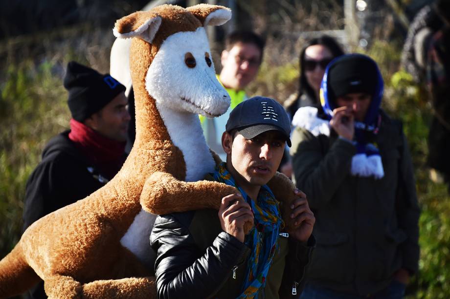 Homem carrega um canguru de pelúcia em suas costas após o esvaziamento do acampamento de refugiados, que ficou conhecido como a 'Selva' de Calais, na França - 28-10-2016