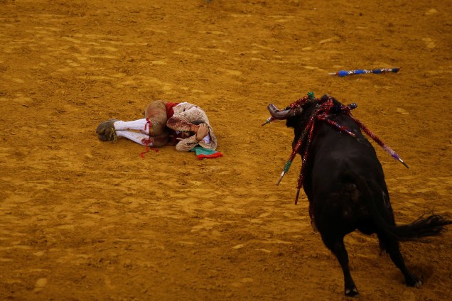 Toureiro se encolhe no chão após ser arremessado por um touro durante sua apresentação em Lisboa, Portugal - 14/10/2016