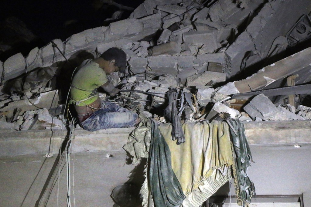 Menino aguarda para ser resgatado após bombardeio em Alepo
