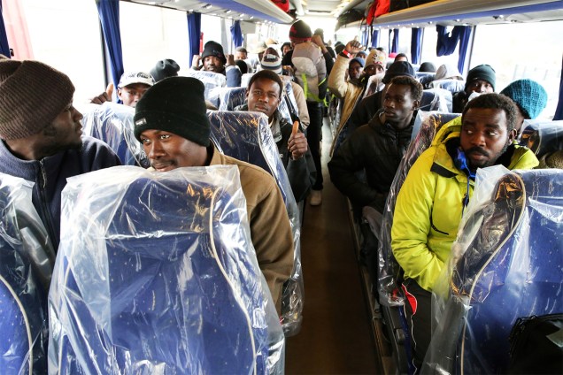Refugiados são transportados para centros de acolhimento, em ônibus com plásticos cobrindo os assentos, após evacuação do acampamento montado no campo de Calais, na França - 26/10/2016