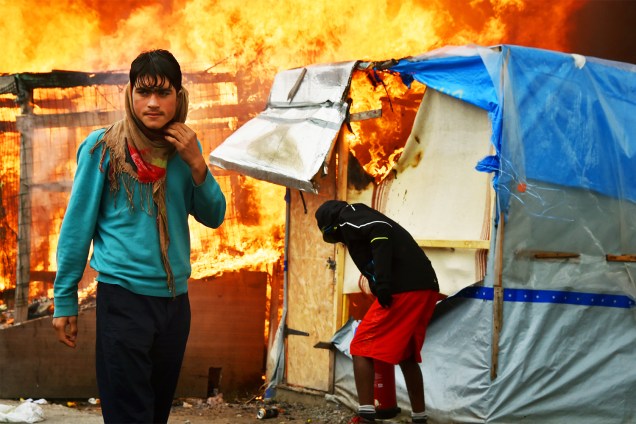 Refugiado observa incêndio em barracas no campo de Calais, na França - 26/10/2016