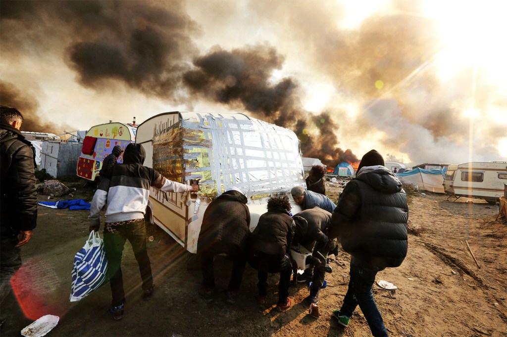 Barracas são incendiadas durante o terceiro dia de evacuação do acampamento montado no campo de Calais - 26/10/2016