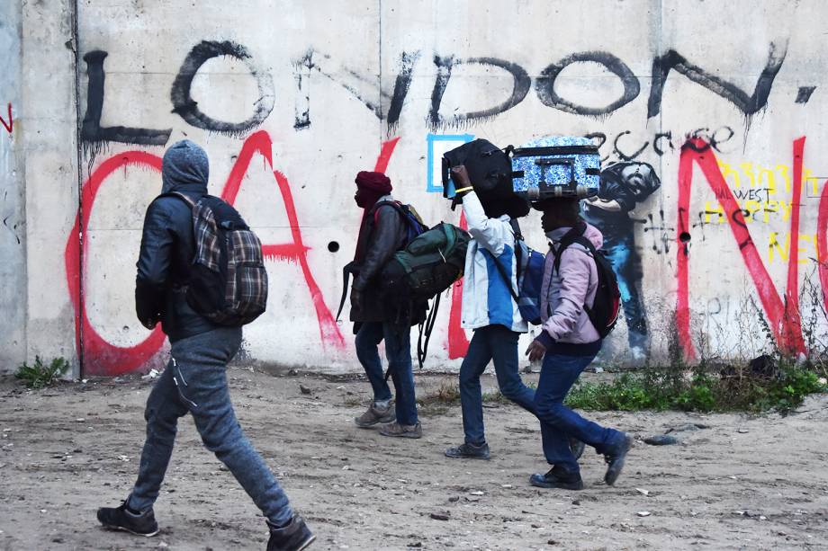 Migrantes carregam suas bagagens durante evacuação do acampamento de refugiados localizado em Calais, na França - 24/10/2016