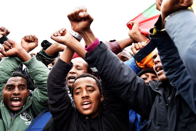 Migrantes da Etiópia cruzam os braços em sinal de protesto durante a evacuação do acampamento de refugiados localizado em Calais, na França - 24/10/2016