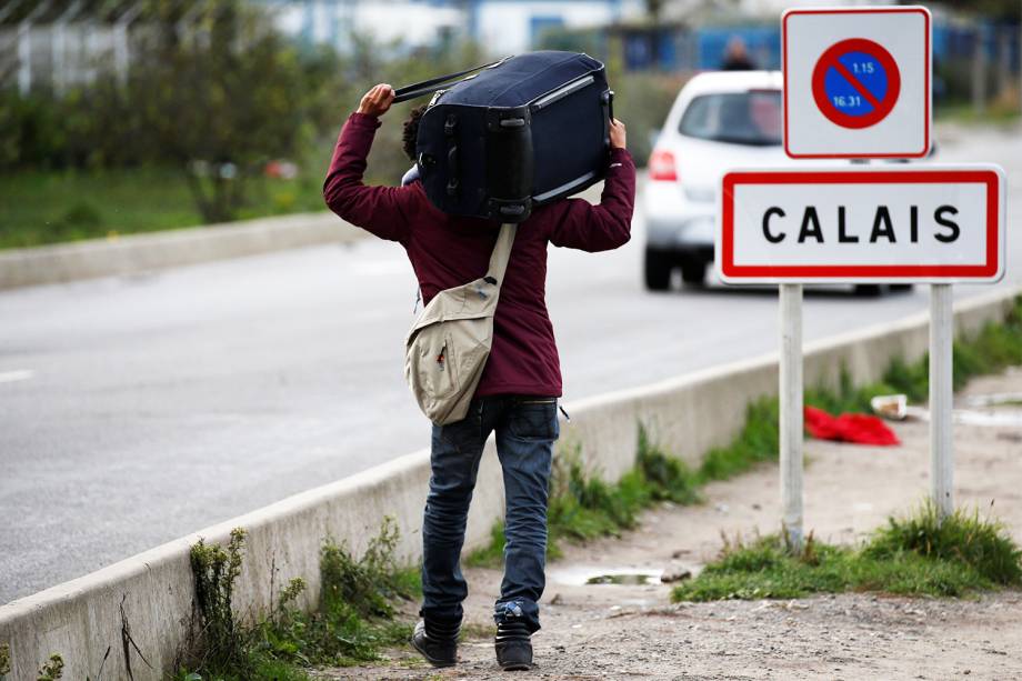 Migrante carrega seus pertences após operação policial no acampamento improvisado de refugiados localizado em Calais, na França - 24/10/2016