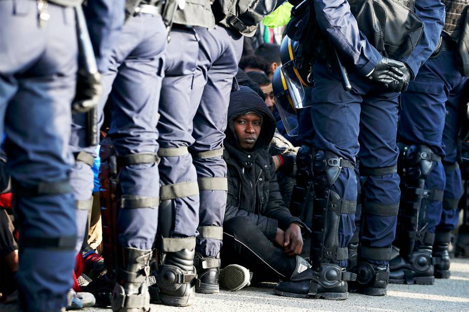 Policiais franceses ficam próximos de migrantes, durante operação de evacuação do acampamento improvisado de refugiados em Calais - 25/10/2016