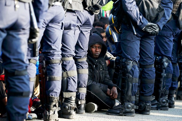 Policiais franceses ficam próximos de migrantes, durante operação de evacuação do acampamento improvisado de refugiados em Calais - 25/10/2016
