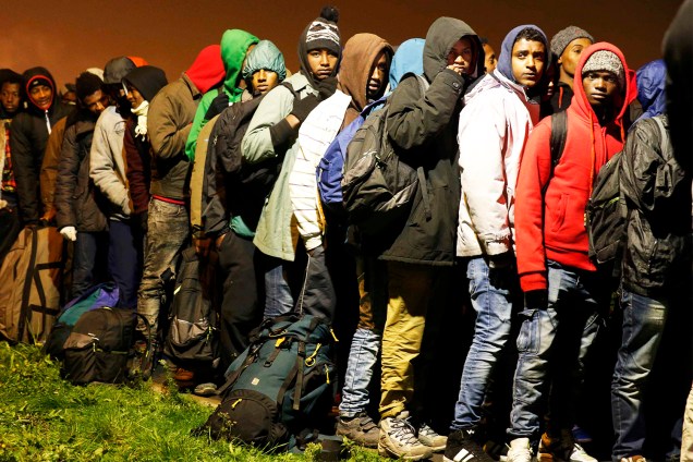 Migrantes aguardam para serem transferidos para centros de acolhimento, após evacuação do acampamento improvisado de refugiados localizado em Calais, na França - 24/10/2016
