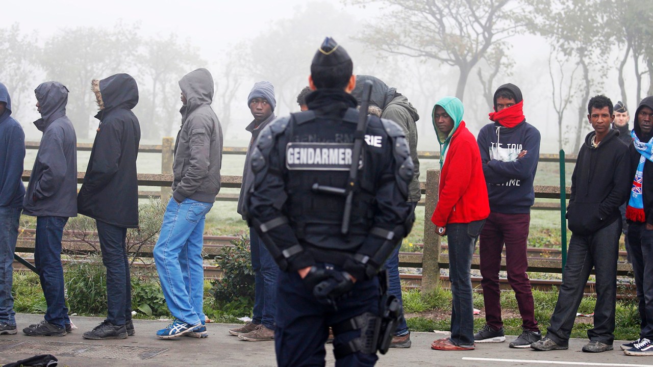 Policial francês acompanha migrantes no campo de Calais, na França, que serão transferidos para centros de acolhimento - 26/10/2016
