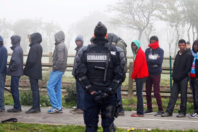 Gendarme francês acompanha migrantes no campo de Calais, na França, que serão transferidos para centros de acolhimento - 26/10/2016