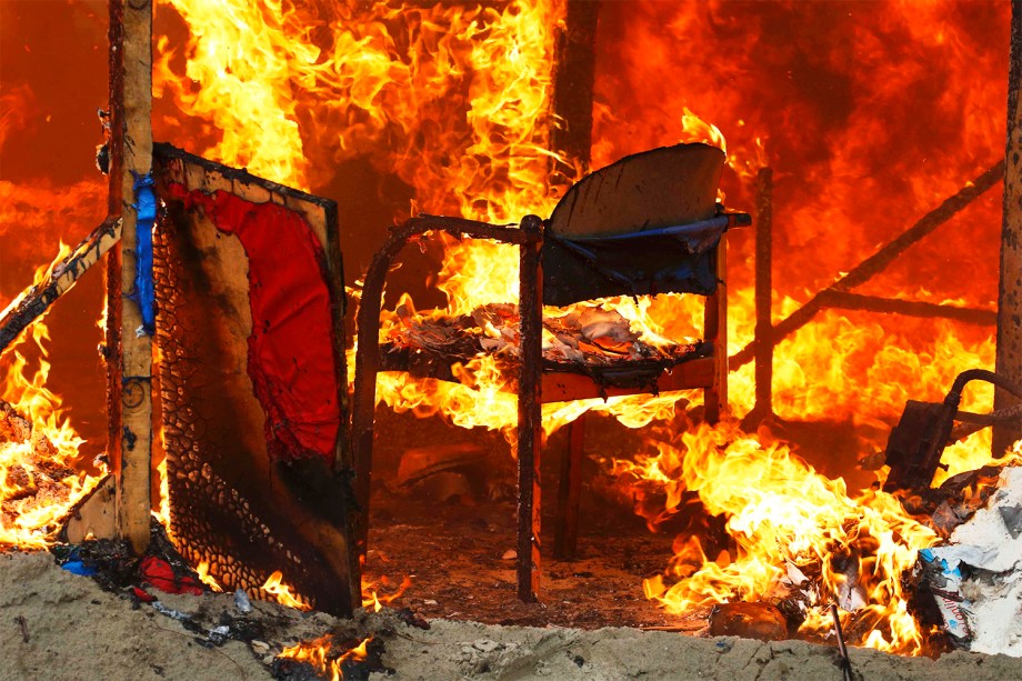 Chamas incendeiam cadeira dentro de abrigo localizado no campo de Calais, na França, durante o terceiro dia de evacuação do local - 26/10/2016