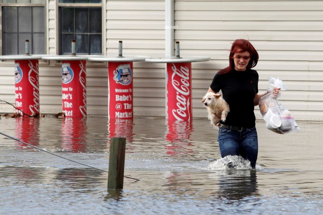 Mulher carrega seu cão no colo enquanto caminha em uma rua inundada após a passagem do furacão Matthew em Garden City, no estado americano da Georgia - 08/10/2016