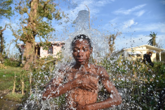 Adolescente toma banho em um chuveiro de uma fonte de água em Houk, zona rural de Les Cayes, área danificada pelo furacão Matthew, no Haiti - 09/10/2016