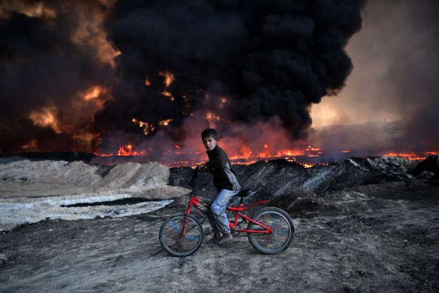 Garoto é fotografado em frente a um campo de petróleo incendiado, durante ofensiva do exército iraquiano contra o Estado Islâmico em Mosul - 21/10/2016