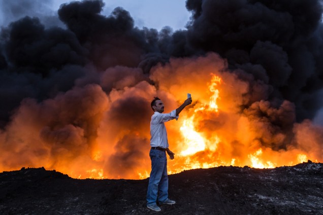 Homem faz uma selfie em frente poço de óleo  incendiado em Qayyarah, ao sul de Mosul - 19/10/2016