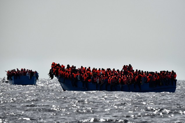Imigrantes aguardam por resgate em uma embarcação superlotada e à deriva no Mar Mediterrâno, ao norte da costa Líbia
