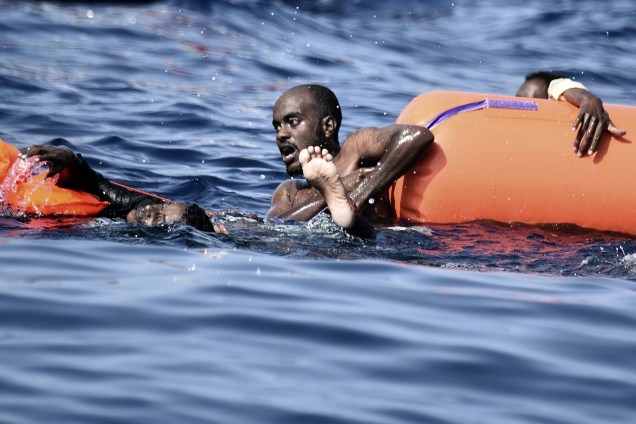 Imigrantes se agarram em boias enquanto esperam para serem resgatados no Mar Mediterrâneo