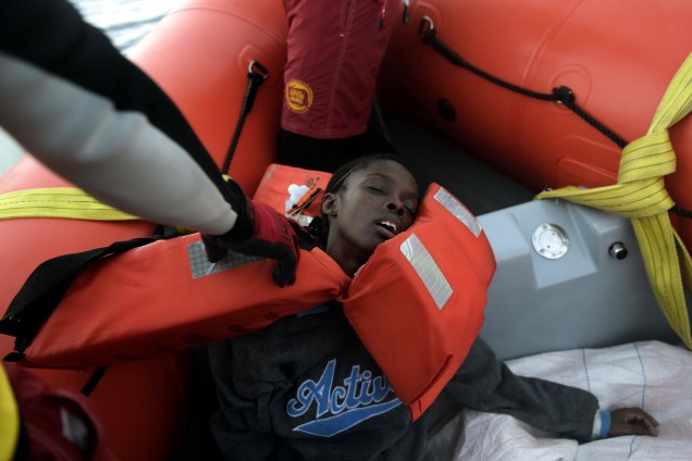 Mulher desmaia após ser resgatada de uma embarcação superlotada de imigrantes e refugiados no Mar Mediterrâneo
