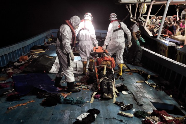 Membros da organização humanitária Proactiva Open Arms retiram o corpo de um imigrante de uma das embarcações durante operação de resgate no Mar Mediterrâneo