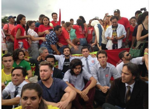 Integrantes do Movimento Brasil Livre formam linha de resistência, sentados: atrás, os fascistas de vermelho