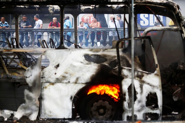 Pedestres observam ônibus queimado durante protesto na Alerj - 16/11/2016