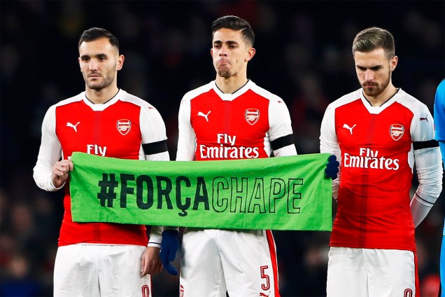 Os jogadores do Arsenal, Lucas Perez, Gabriel Paulista e Aarom Ramsey seguram faixa com a hashtag '#ForçaChape', em homenagem às vítimas do voo que transportava a equipe catarinense - 30/11/2016