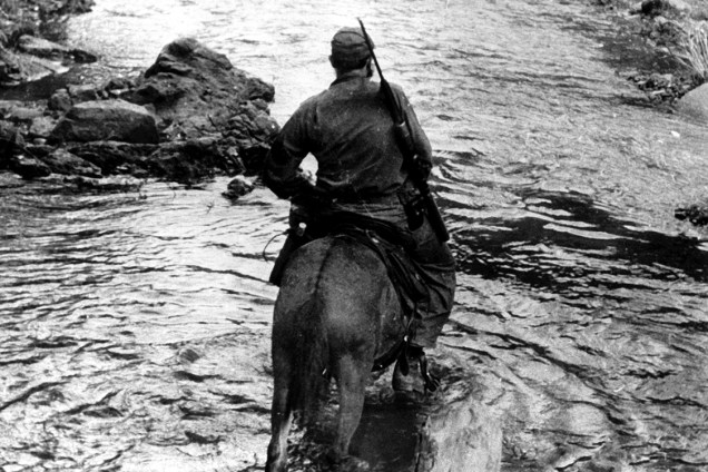 Fidel Castro tenta atravessar um riacho em cima de seu cavalo em Sierra Maestra, leste de Cuba, onde avançava com seu exército na tentativa de depor o ditador Fulgencio Batista, em dezembro de 1958