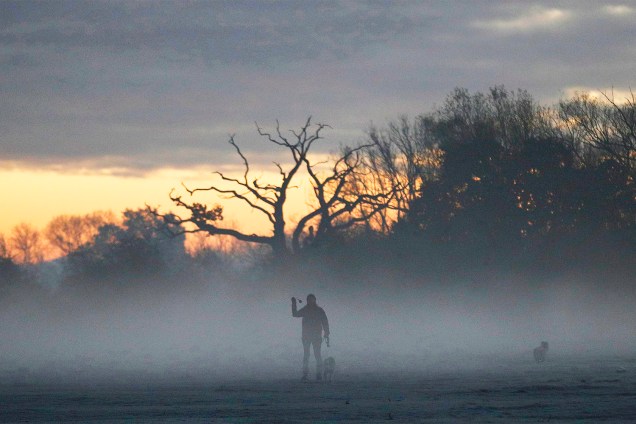 Mulher caminha com cão em manhã de névoa na região de Quorn, na Grã-Bretanha - 08/11/2016