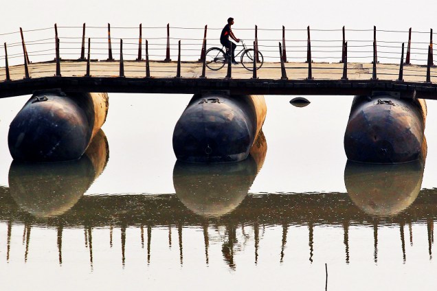 Ciclista atravessa ponte improvisada sobre o rio Ganges, em Allahabad, na Índia - 07/11/2016