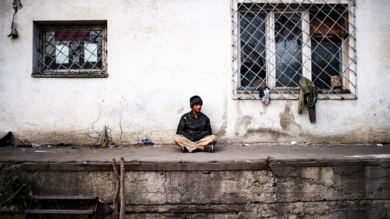 Migrante se senta na frente de armazém abandonado em Belgrado, capital da Sérvia - 16/11/2016
