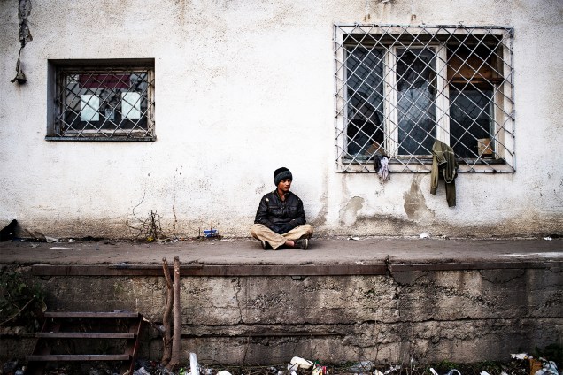 Migrante se senta na frente de armazém abandonado em Belgrado, capital da Sérvia - 16/11/2016