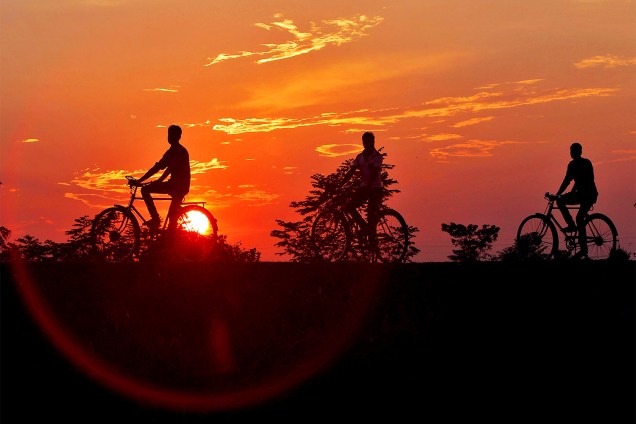Homens pedalam bicicletas durante pôr do sol nos arredores de Agartala, na Índia - 01/11/2016